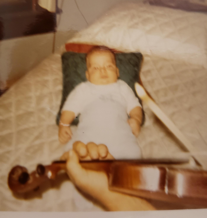 Photo: Greg as an infant, listening to Mac play the fiddle, 1970